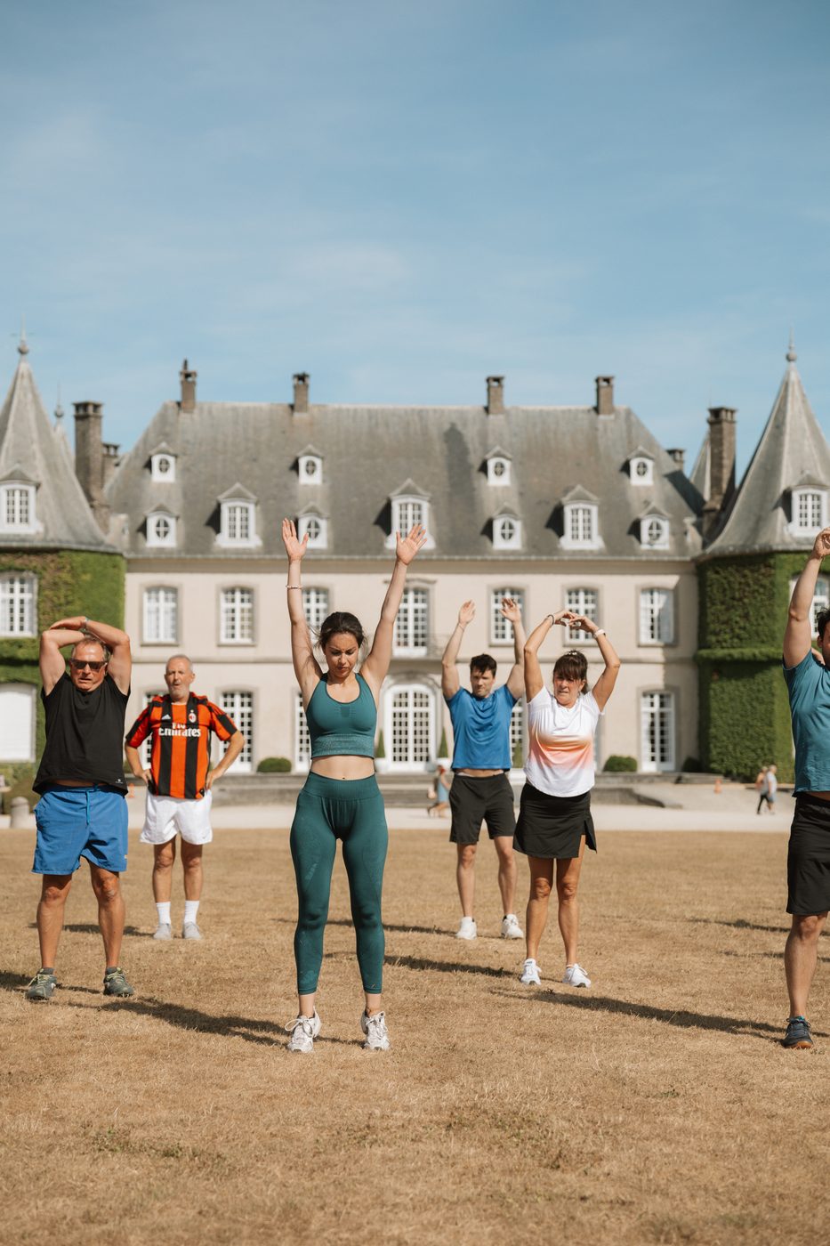 Participants bras levés lors d'une séance PACE dans le parc du château